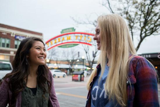 两个年轻女人在城市市场标牌外聊天
